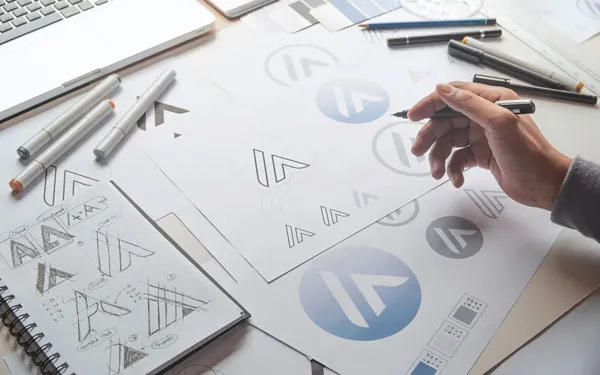 デザイナーがデスクで紙とペンを使い、ロゴのデザインに取り組む制作現場