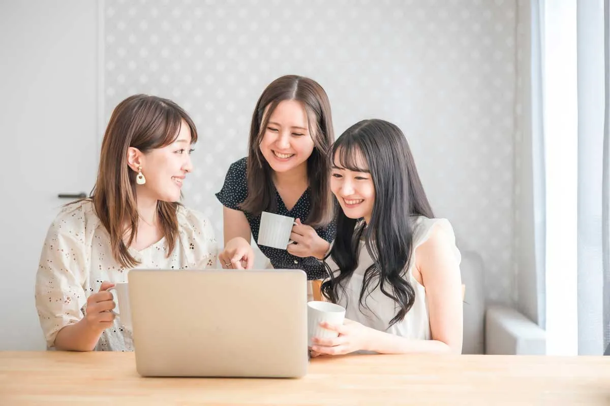 完成したホームページを見ながら談話する女性3人